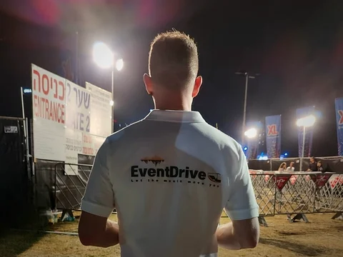 איש צוות בחולצת EventDrive עומד מול שער הכניסה למתחם המופע